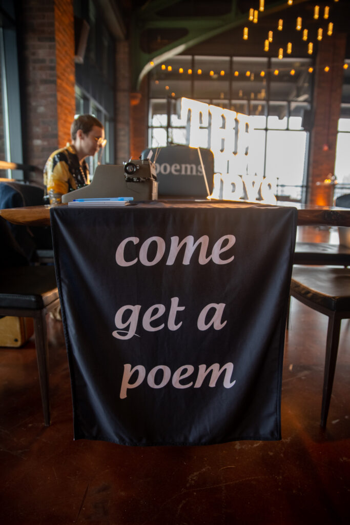 Live Art International's Poets, A Table With &Quot;Cpme And Get A Poem&Quot; Sign