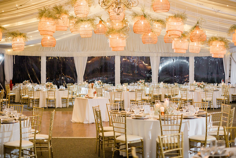 Tables With Tablecloth, Golden Chairs, White Drape Wall And Rattan Lanterns Wedding Lighting Above