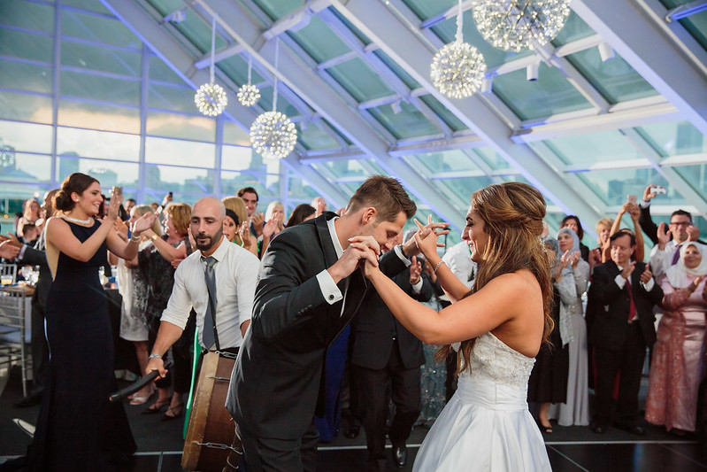 Bride And Groom Dancing With Their Guests Under The Sphere Shape Chandeliers At Solarium