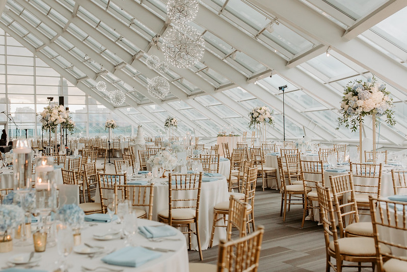 Tables And Chairs With White Floral Decor And Hanging Sphere Shape Chandeliers Above