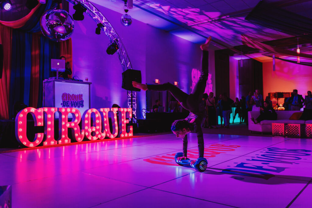 Marquee Letters Spelling Out &Quot;Cirque&Quot;, Purple Uplighting And A Female Performer