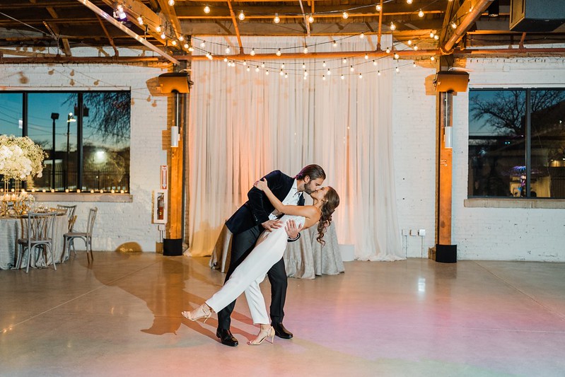 Bride And Groom Shared A Kiss Under The String Lights And White Drape As Their Backdrop