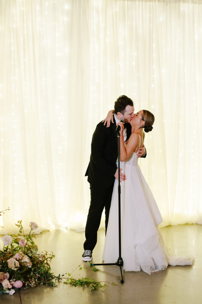 Hannah And Declan Kissing With Drape Twinkle Lights As Their Backdrop