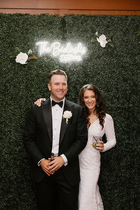 Bride And Groom With Greenery Wall As Their Backdrop