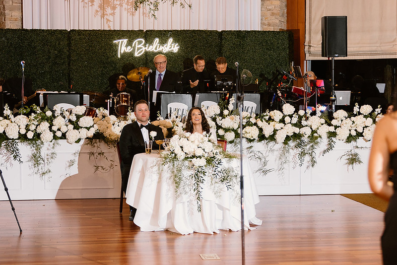 bride and groom with greenery wall rental as their backdrop