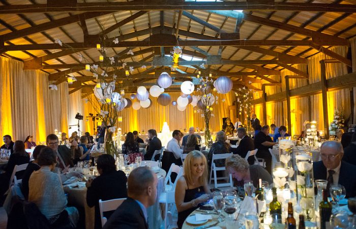 Wedding Guest Happily Seated On Their Tables With Hanging Paper Lanterns Above Them